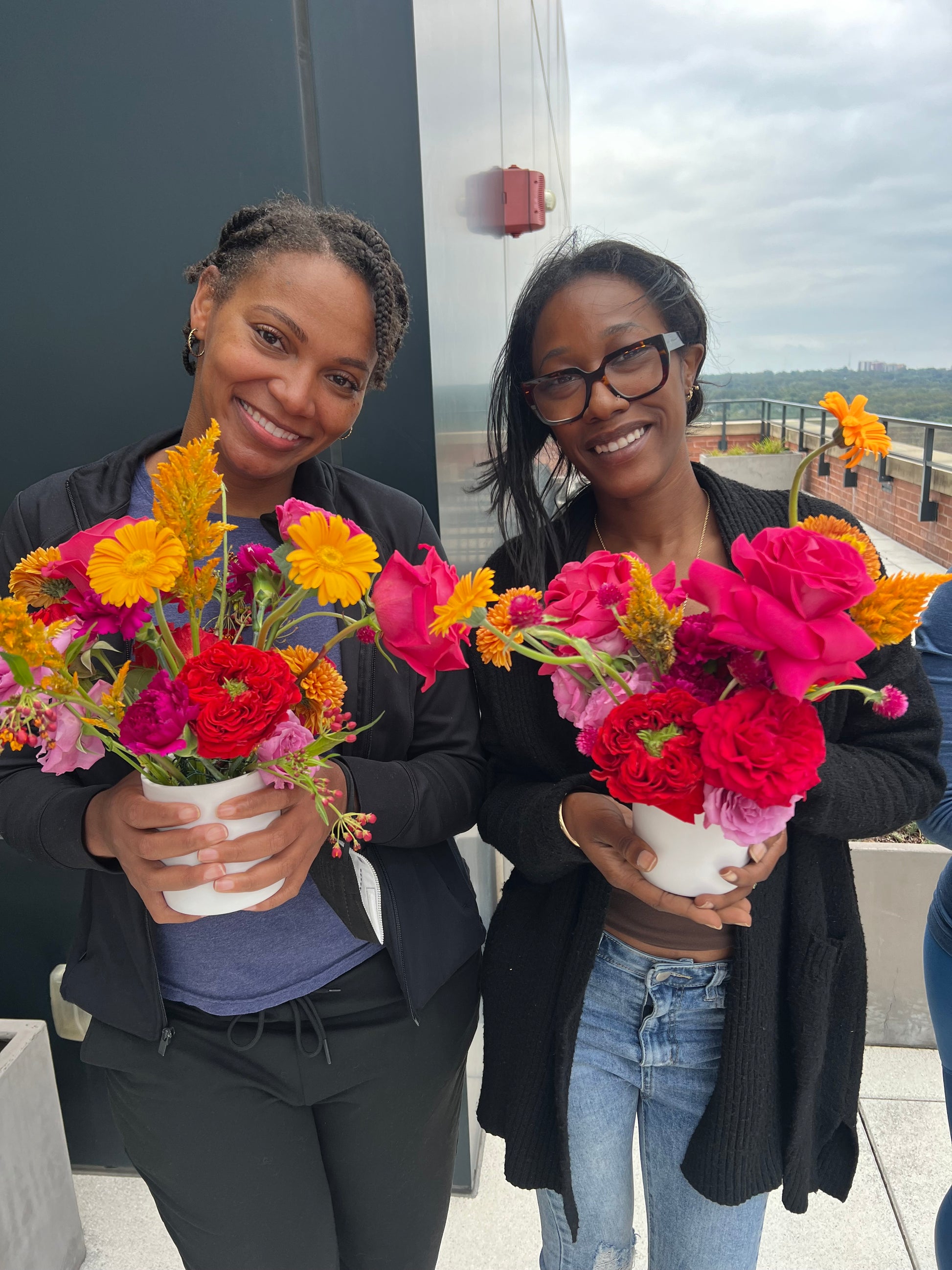 Two women holding colorful flowers with a blurred background
