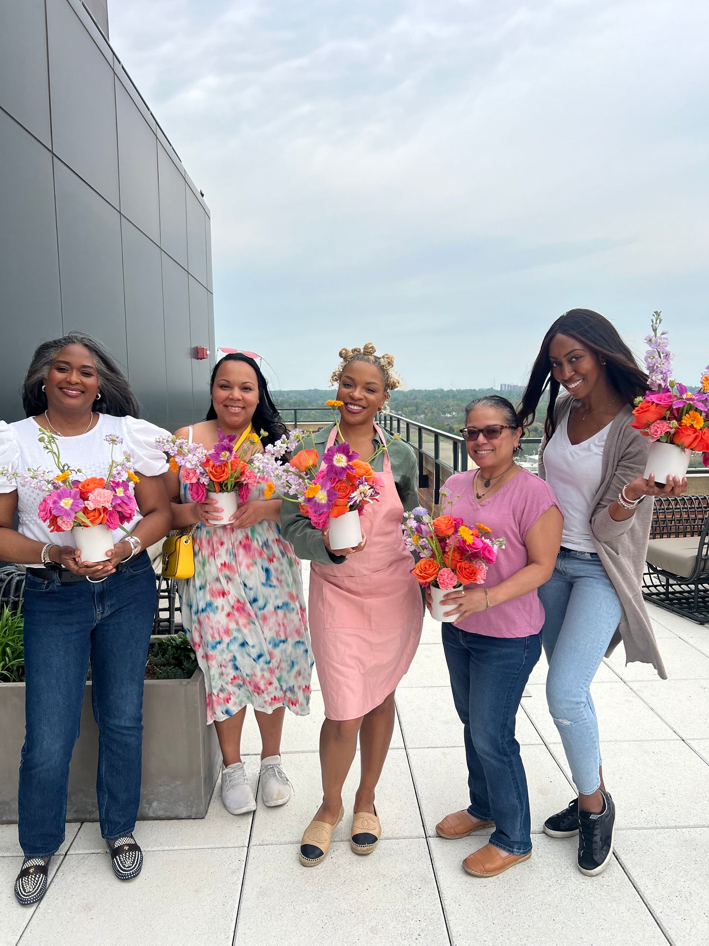 Group of people posing together with colorful flower arrangements in an indoor setting.