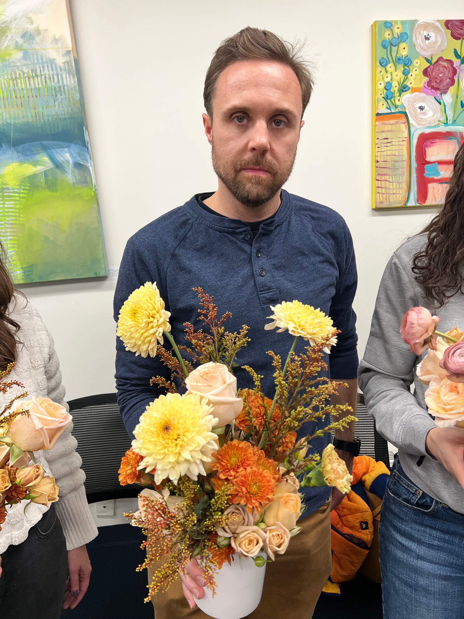 Man holding a bouquet of flowers with a colorful painting in the background